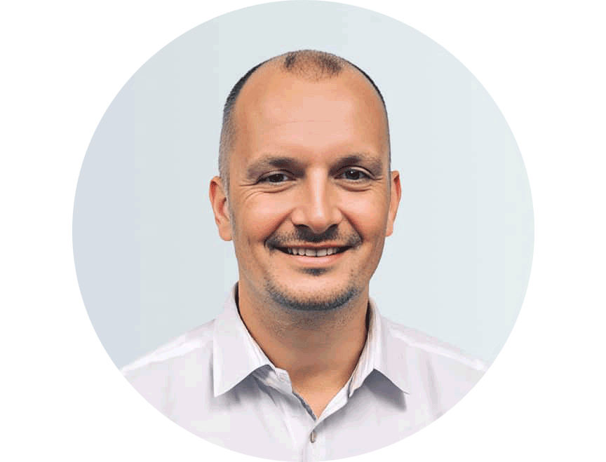 Porträtfoto von Kristian Lempa in weißem Hemd vor hellgrauem Hintergrund, kreisförmig zugeschnitten.