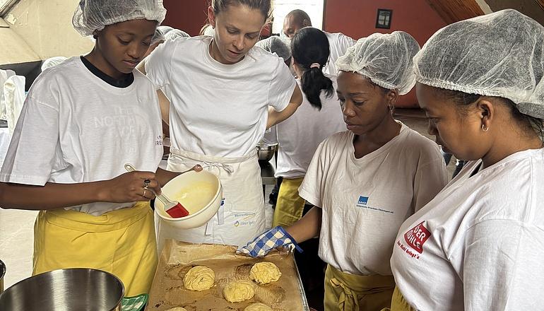 Bäckermeisterin Sarah Braun steht an einem Tisch mit drei angehenden Bäckerinnen aus Madagaskar.