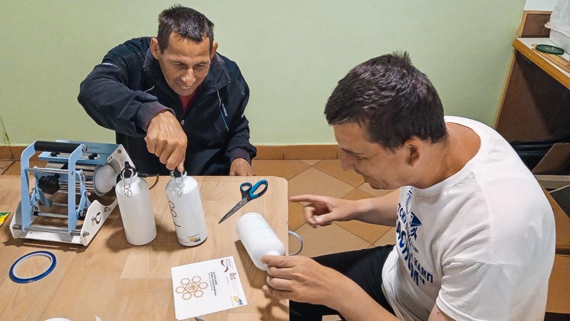Two persons are working together at a table, labelling water bottles.