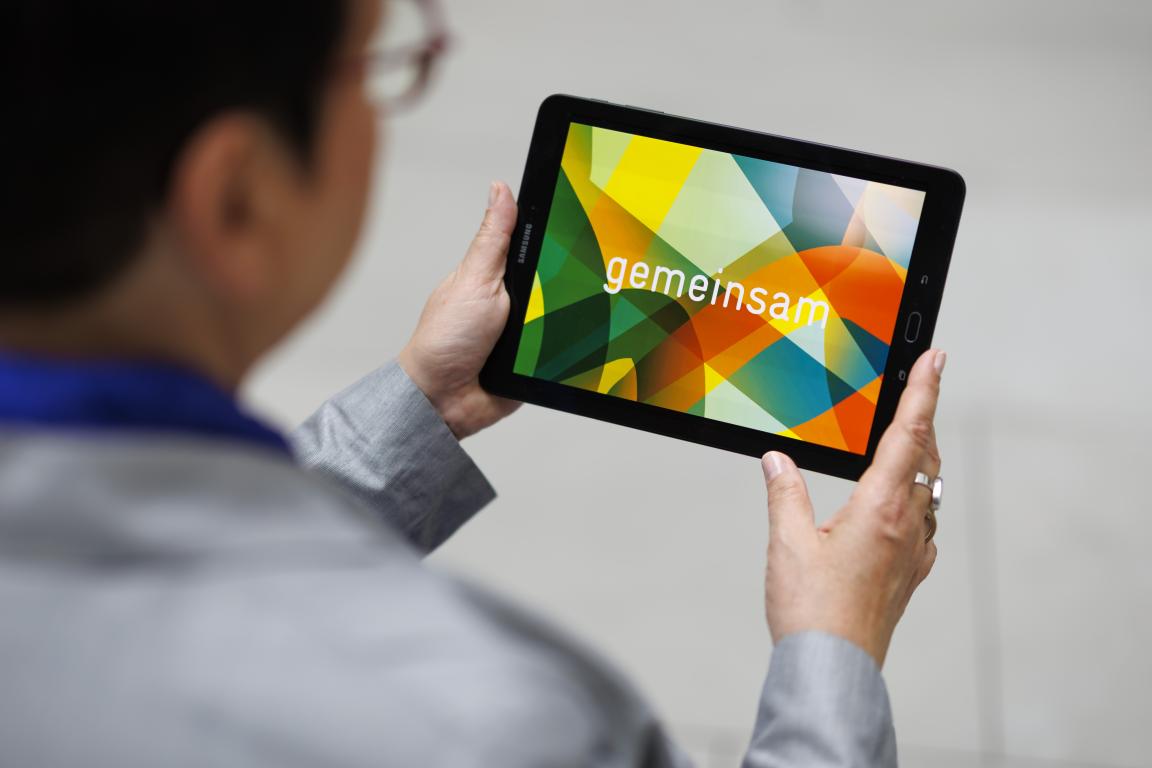 Eine Frau schaut auf ein Tablet, das sie in den Händen hält.
