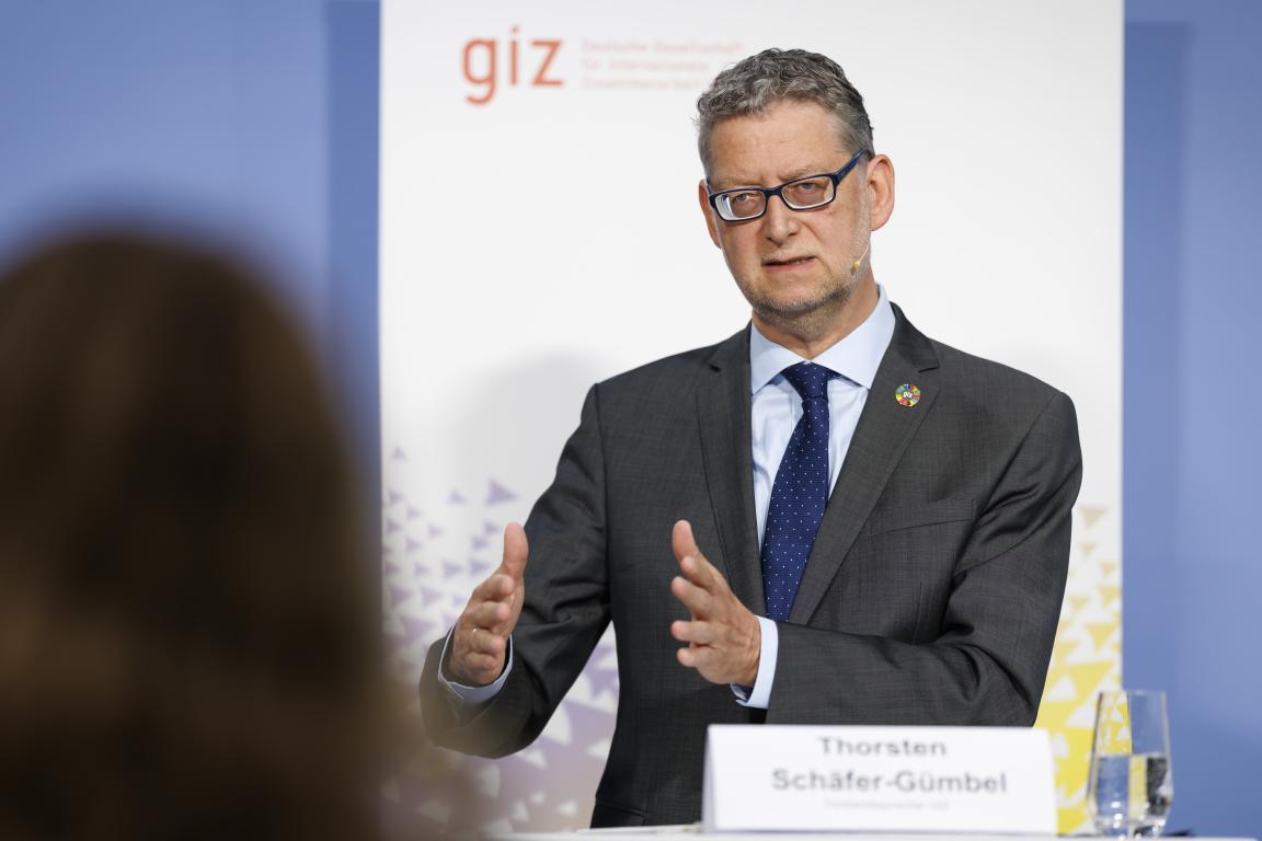 Ein Mann in Geschäftskleidung gestikuliert vor einem Rollup mit dem Logo der GIZ. Vor ihm ein Namensschild mit der Aufschrift Thorsten Schäfer-Gümbel. 