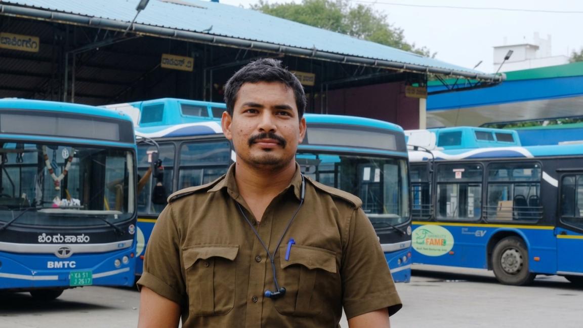 A bus driver standing in front of a fleet of electric buses.