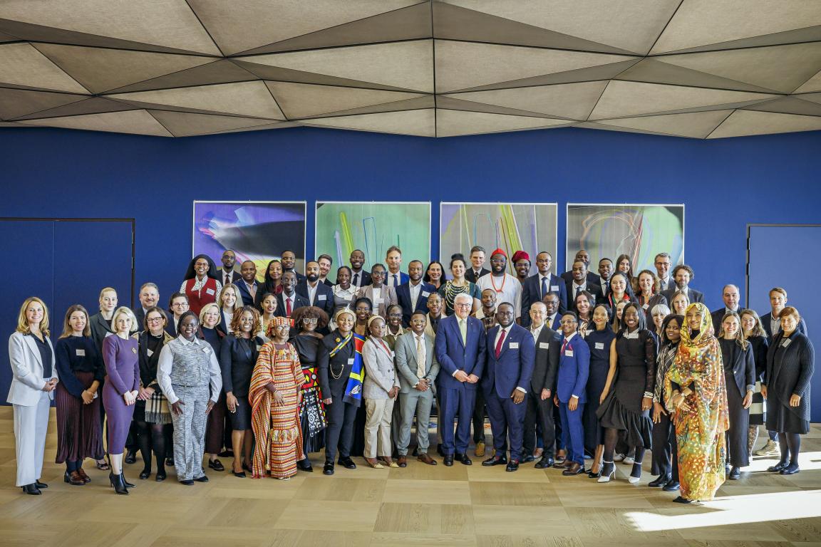Ein Gruppenfoto zeigt viele Personen vor einer blauen Wand
