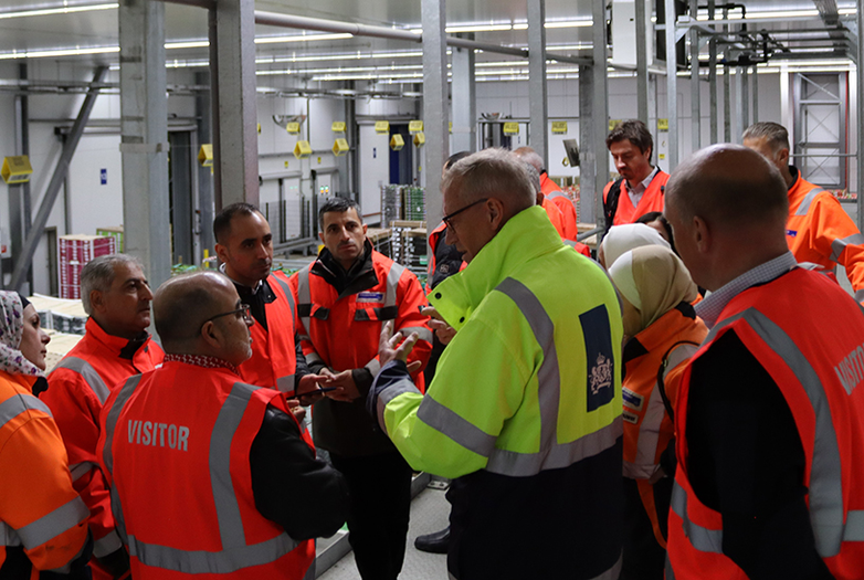 Eine Gruppe von Männern in Arbeitskleidung erhält Arbeitshinweise.
