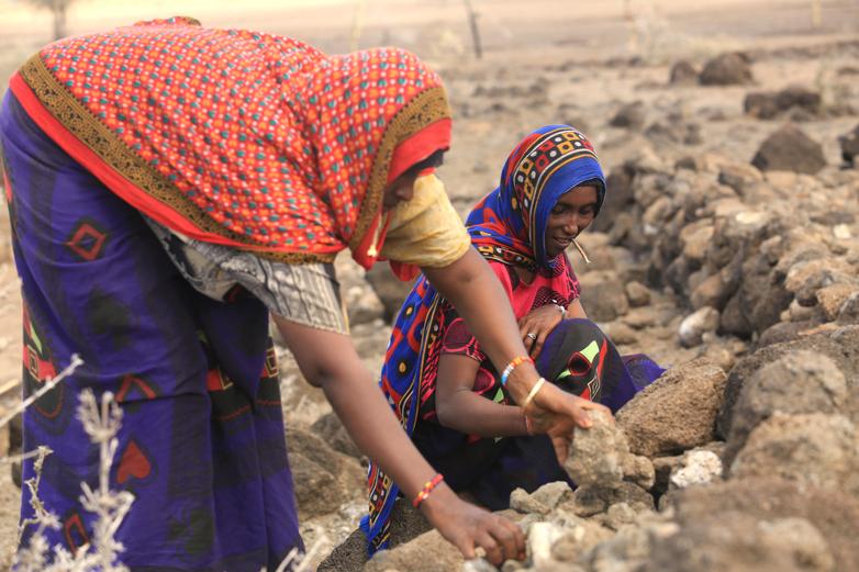 Women working with stones outdoors.