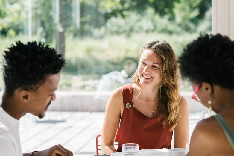 Three people are sitting at a table, smiling and talking.