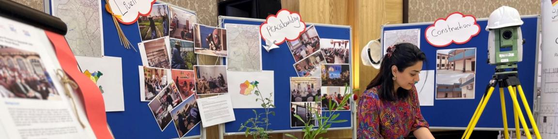 Eine Frau die in der Nähe von Plakaten mit Karten und Bildern steht.