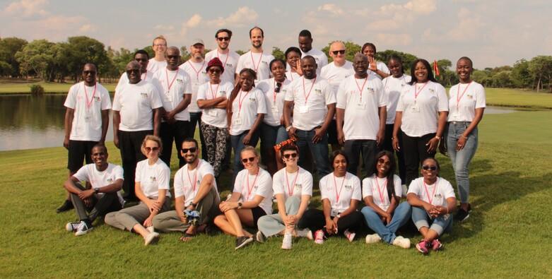 A group of people pose for a photo in a green park.