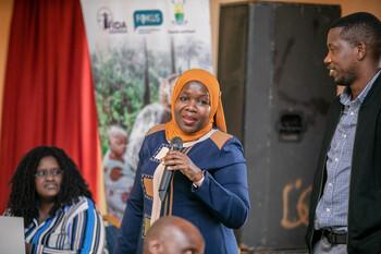 A woman with a headscarf speaks into a microphone.