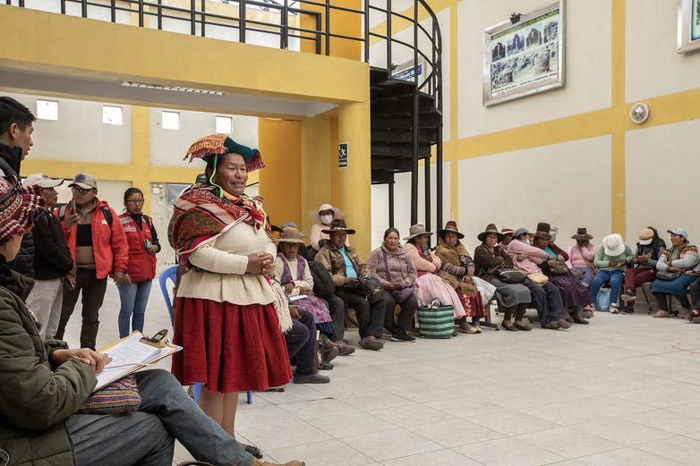 Craftspeople, some sitting and some standing, holding a meeting in a room.