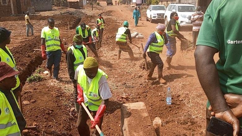 Menschen bauen an einer unbefestigten Straße.