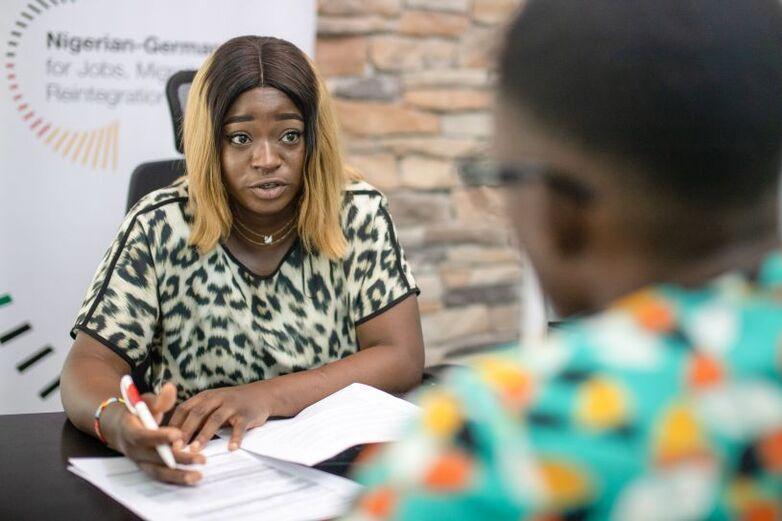 Eine Frau sitzt einer Person gegenüber und füllt Dokumente gemeinsam mit ihr aus.