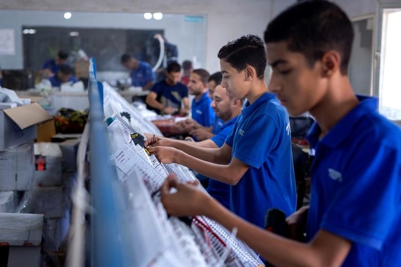 Eine junge Auszubildende arbeitet in einer elektrotechnischen Werkstatt.