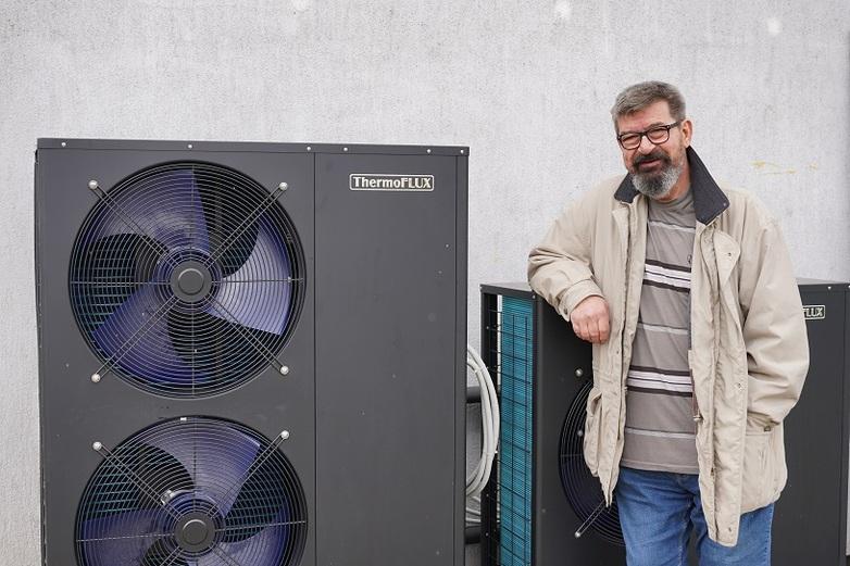 A man stands next to a new energy-efficient heating system for his house in Bosnia and Herzegovina.