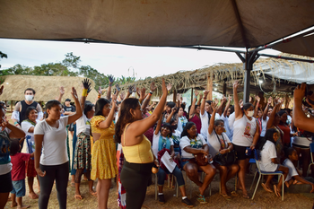 Frauen zeigen bei einer Abstimmung mit den Händen auf.