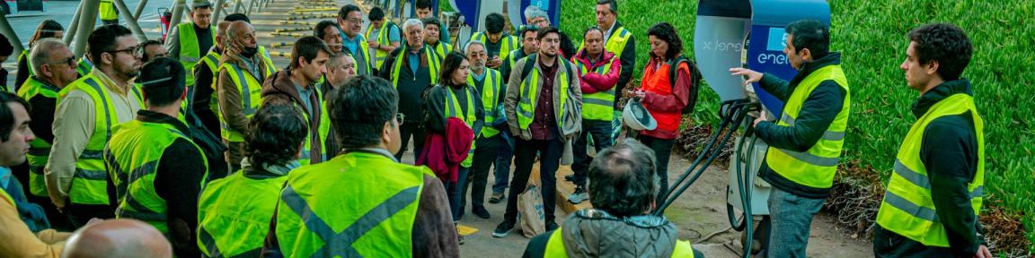 Ein Mann erklärt einer Gruppe eine E-Ladesäule an einem Elektrobusbahnhof.