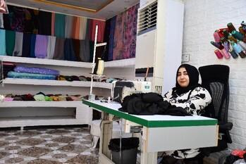 Woman entrepreneur sitting in front of a desk with a sewing machine