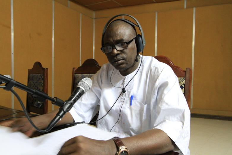 Radio presenter sitting in front of a microphone in the studio.