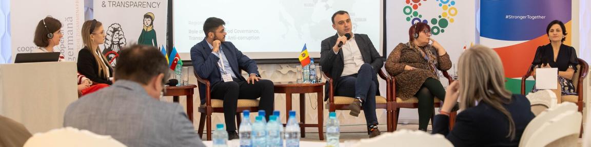 Menschen sitzen bei einer Diskussionsrunde auf einer Bühne.