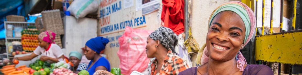 Eine Gemüsehändlerin hinter einem Marktstand.