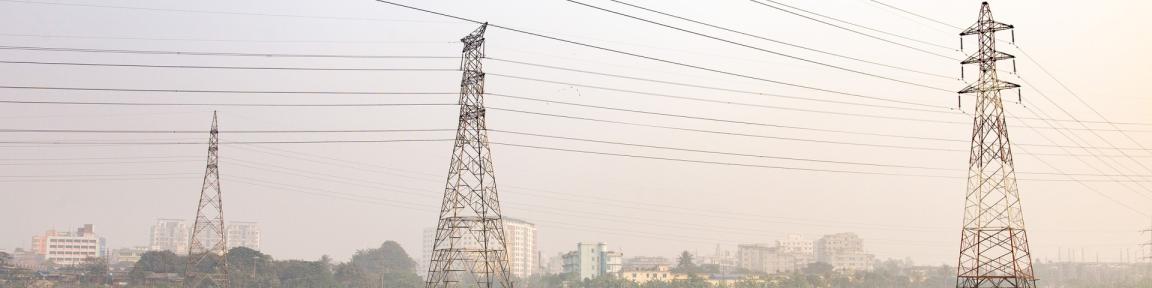 Drei Masten einer Hochspannungsleitung auf einem Feld.