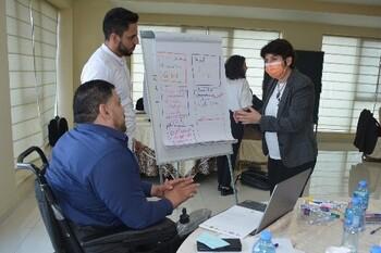 People discuss ideas in front of a flip chart.