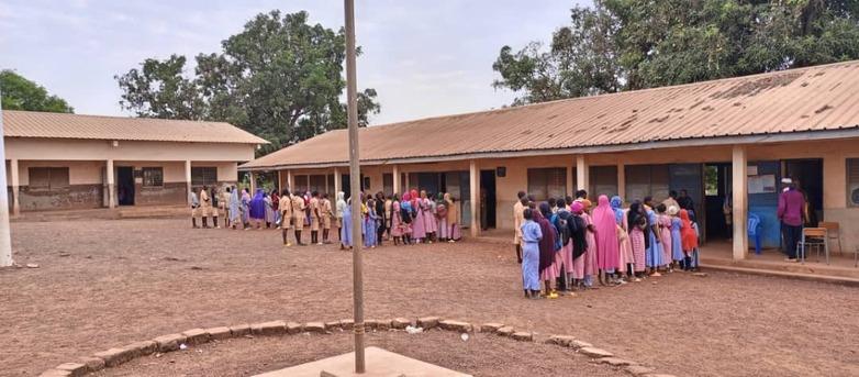 Schüler*innen in Guinea stehen in Schlagen vor einer Schule.