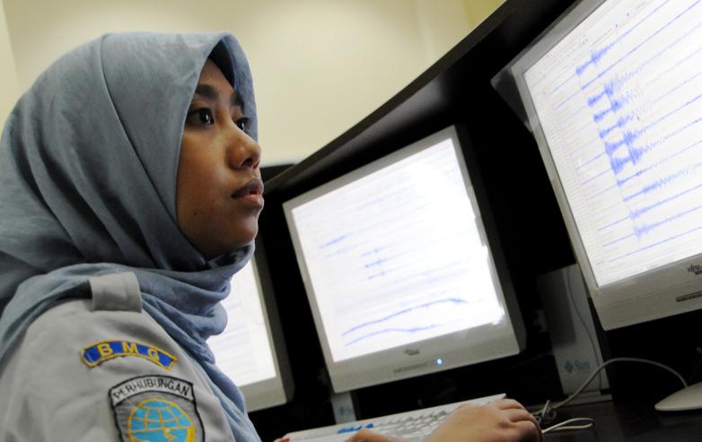 A woman works in front of computer screens.