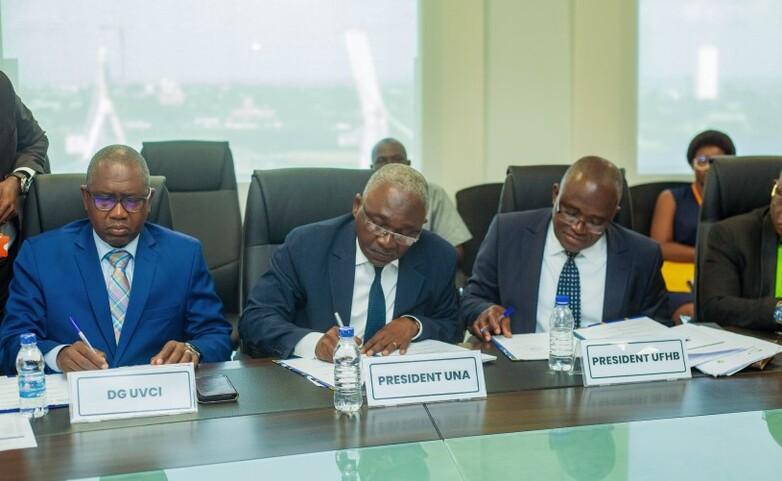 The Ivorian Minister for University Education and university presidents sit at tables together at an event and take notes. © GIZ