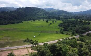 Landschaft im nationalen Schutzgebiet Hin Nam No in Laos mit grüner Vegetation, bewaldeten Hügeln und einer Straße, die die Landschaft durchschneidet.