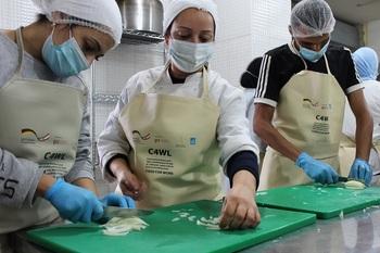 Three cash for work participants chop onions in a kitchen to prepare meals for families in need. © GIZ