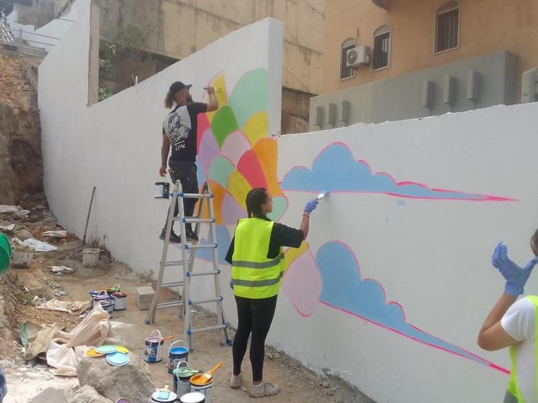 Two people apply colourful paint to the side wall of a staircase.  © GIZ