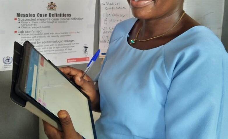 Eine Gesundheitsfachkraft in blauer Uniform in Malawi. Sie nutzt ein Tablet, um die Patienten besser versorgen zu können.