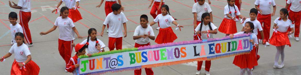 Escolares bailando en el patio de un colegio. Sostienen un cartel que reza “Juntas busquemos la equidad”.