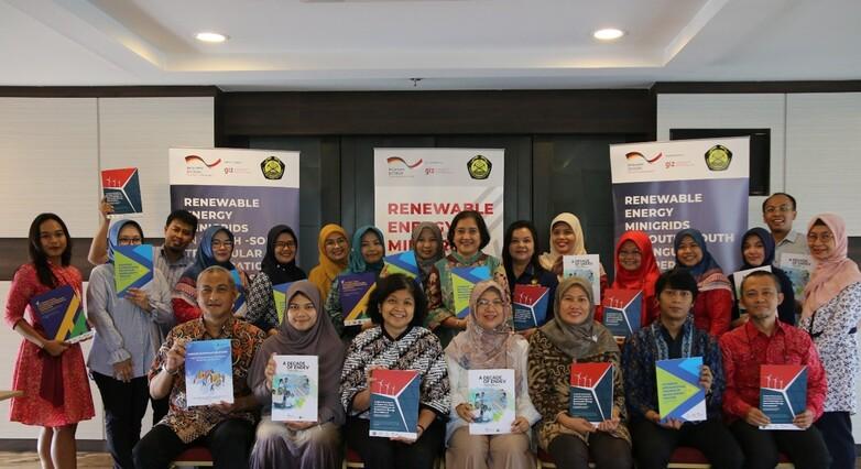 A group of people in front of banners holding brochures.