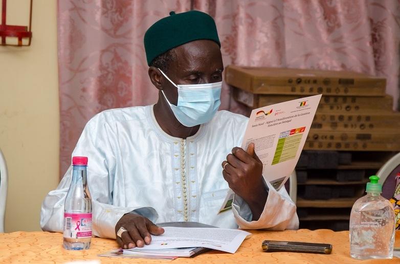 Ein Mann mit OP-Maske ließt ein Dokument.