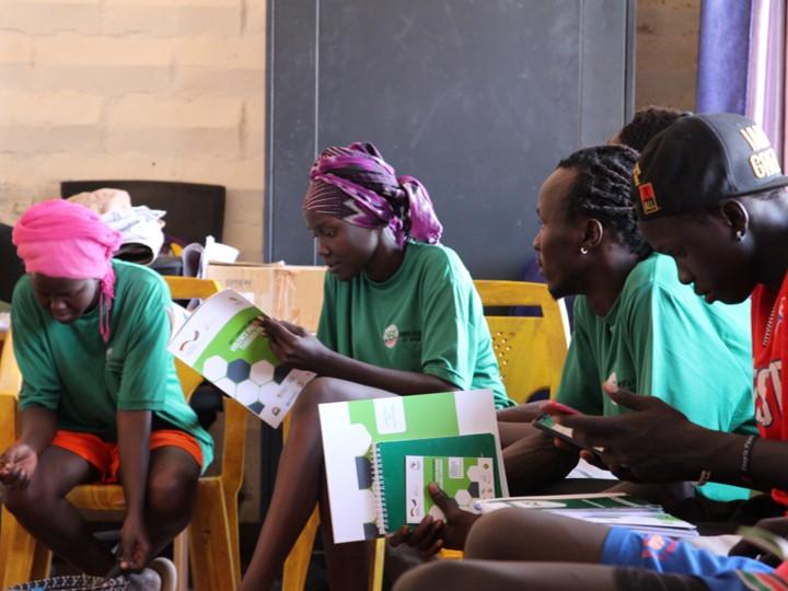 Young people sit together and hold learning materials in their hands.