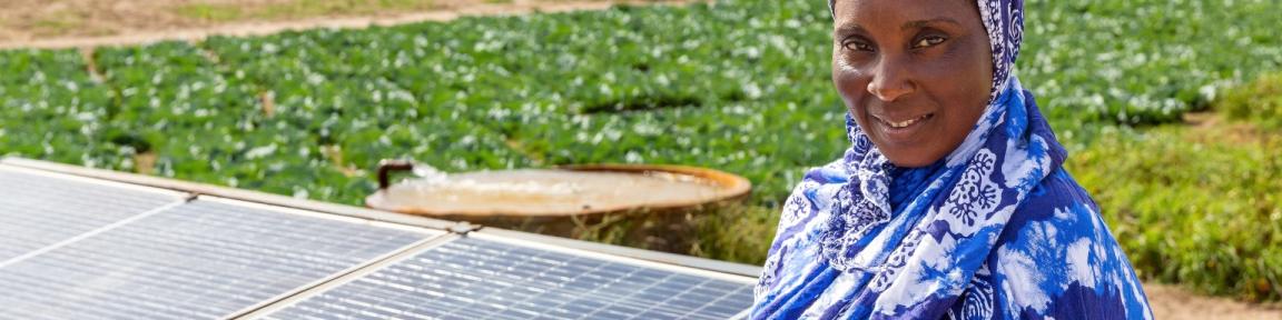 Eine Frau steht neben Solarpaneelen auf einem Feld.