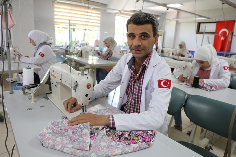 A trainee in a classroom operating a sewing machine.