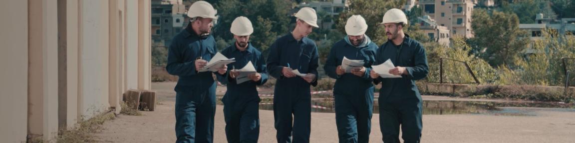 Auszubildende, die über Lehrmaterialien zum Thema mechanische Wartung diskutieren, beim Betreten der Schulwerkstatt.