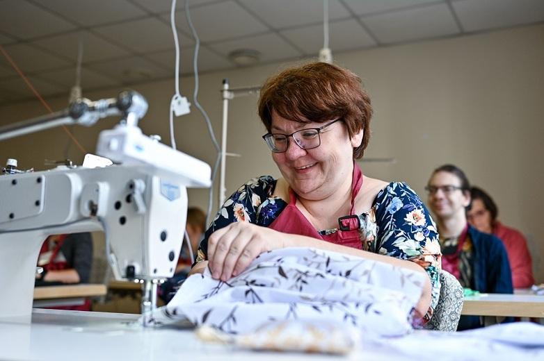 A woman working on a sewing machine in a classroom.