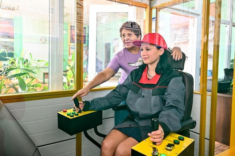 A woman showing a student how to control a machine.