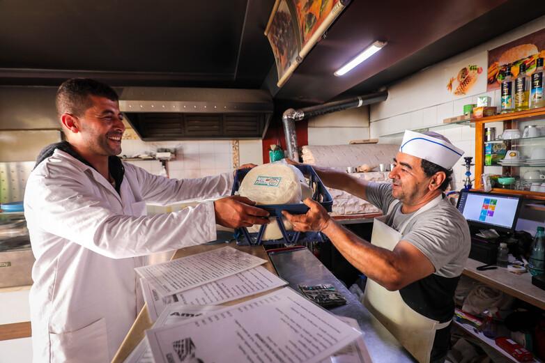 An entrepreneur in Tunisia giving a customer a block of handmade cheese.