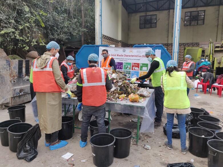 People stand around a table and sort the waste on it. Copyright: GIZ