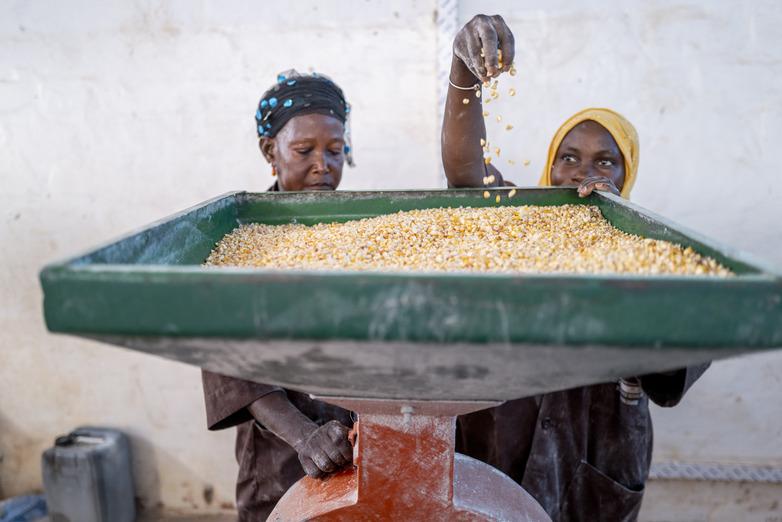 Two women work behind a solar-powered flour mill.