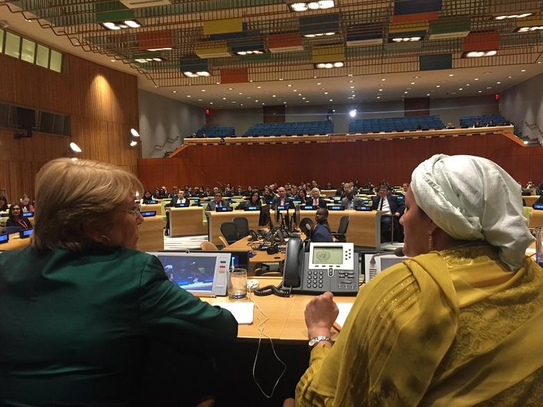 Two people sit next to each other in the General Assembly Hall and converse.