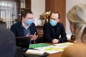 Two men sit and chat at a table, with regional maps laid out in front of them. Copyright: GIZ/Oleksandr Osipov