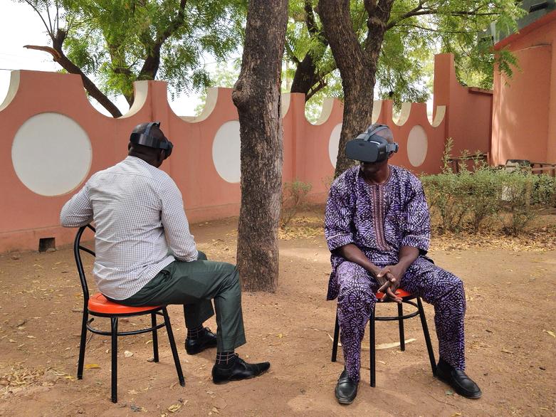 Two men with VR glasses at a training course on sustainable cotton cultivation in Cameroon.