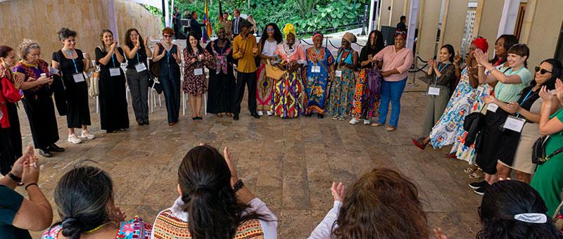 Women stand in a circle and clap their hands. 