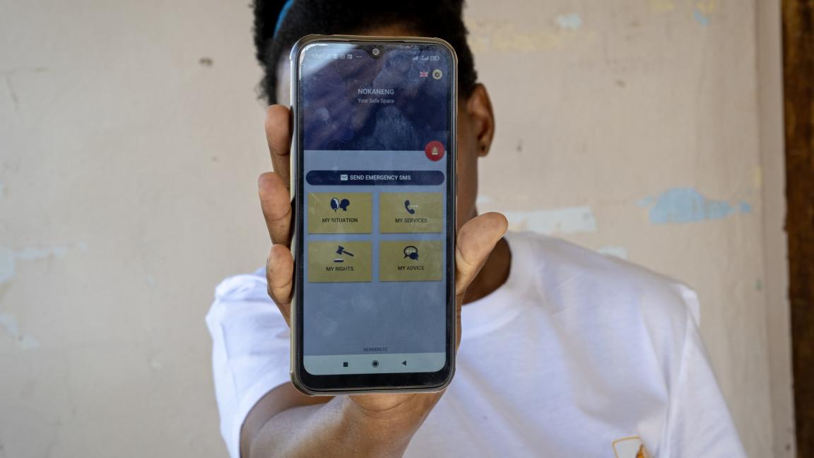 Eine Person zeigt einen Handybildschirm, auf dem die Nokaneng-App geöffnet ist.